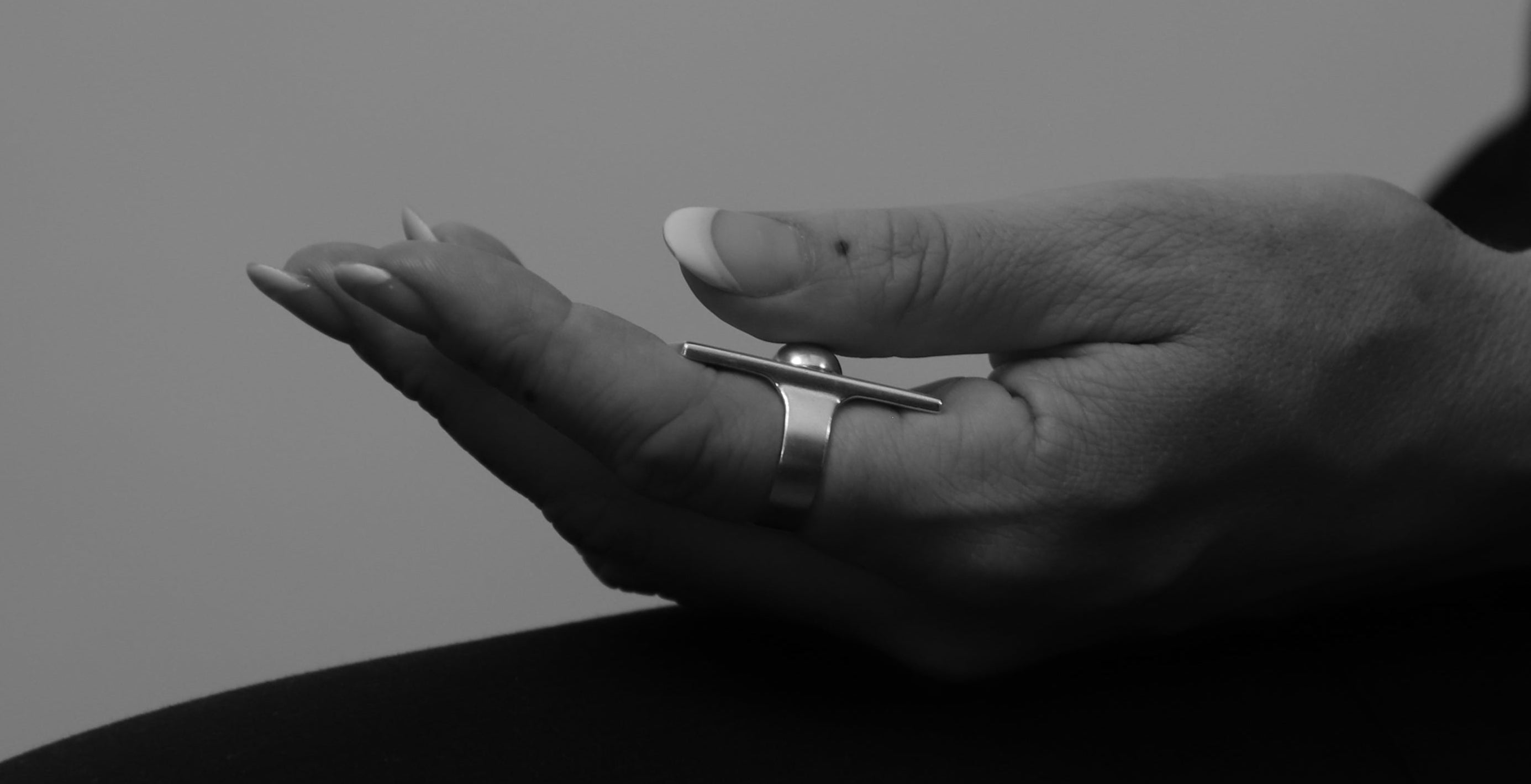 Black and white image of a hand with a ring on a plain background